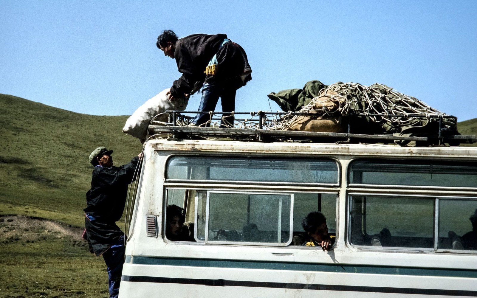 a shared taxi loaded to the roof, passengers waiting alongside